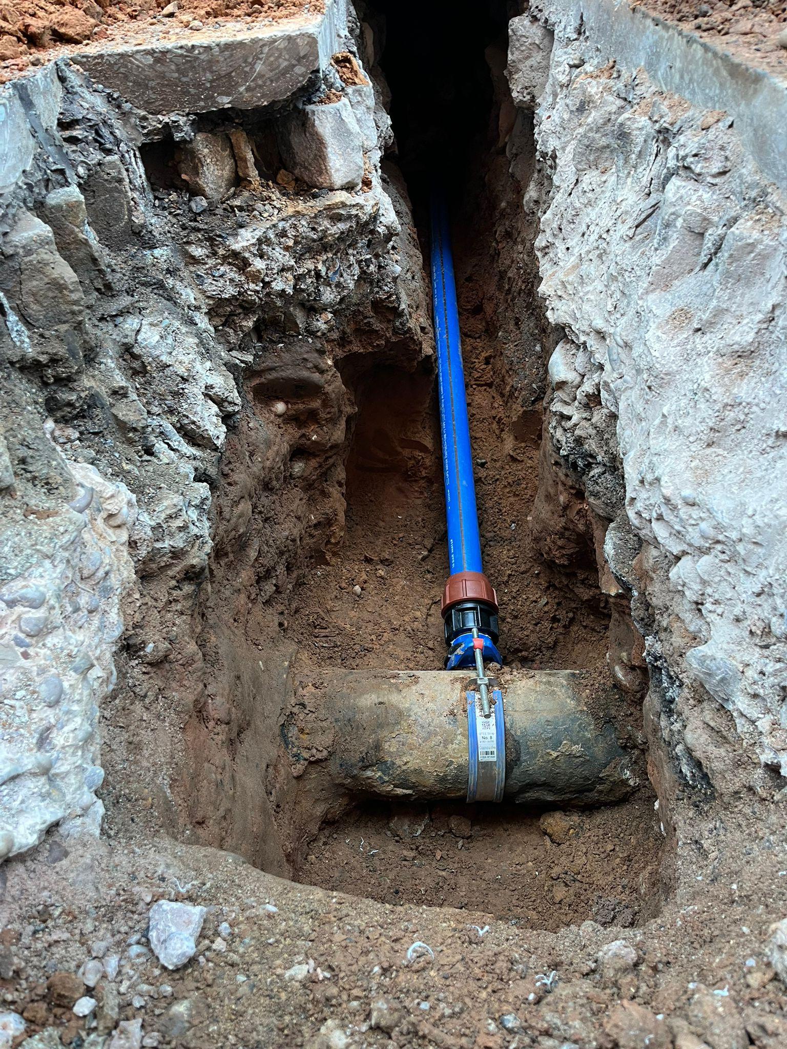Blue PE gas pipe joint in an excavation trench with yellow safety marker tape